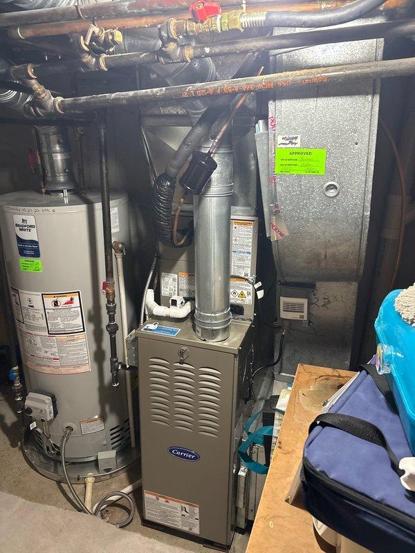 Completed full air conditioning system installation including outdoor Carrier condenser unit positioned on concrete pad with river rock landscaping and indoor air handler/furnace equipment. Installed refrigerant line set routing from outdoor unit to indoor mechanical room, connected all electrical components, verified proper system operation, and ensured all equipment met manufacturer specifications and local code requirements.
