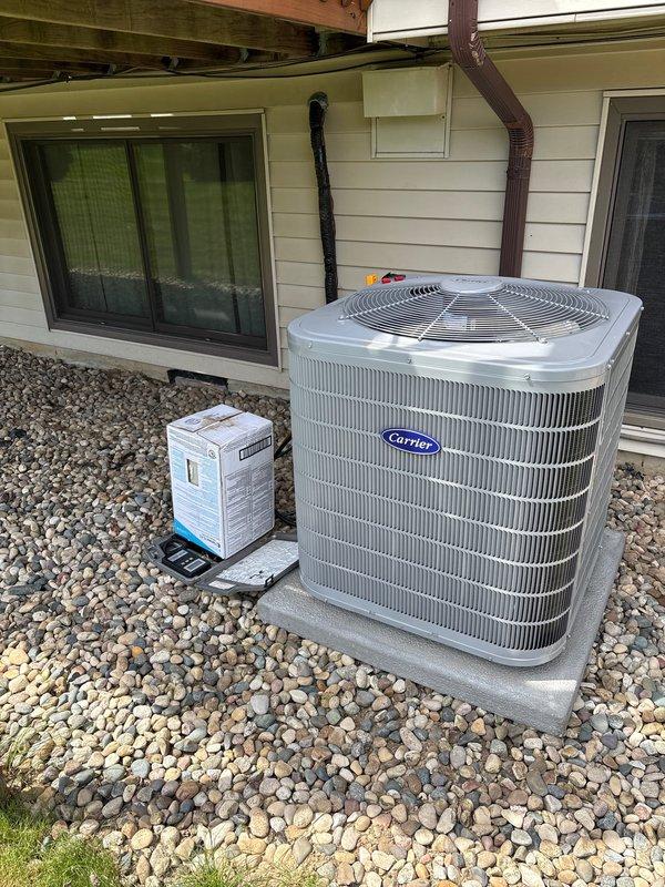 Completed full air conditioning system installation including outdoor Carrier condenser unit positioned on concrete pad with river rock landscaping and indoor air handler/furnace equipment. Installed refrigerant line set routing from outdoor unit to indoor mechanical room, connected all electrical components, verified proper system operation, and ensured all equipment met manufacturer specifications and local code requirements.