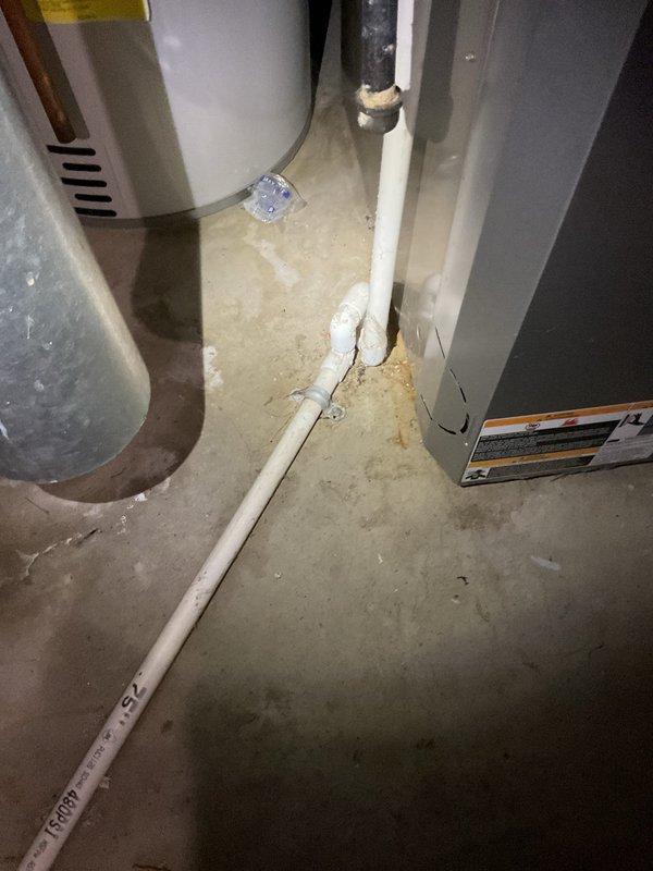 Responded to water leak complaint on 20+ year old Bryant furnace. Upon inspection, found condensate drain system with visible mineral deposits and staining on PVC drain lines. Examined condensate pump assembly with float switch and drainage piping configuration. Verified refrigerant lines and flexible ductwork connections. Documented existing condensate management system showing signs of age-related wear and mineral buildup on drain components.