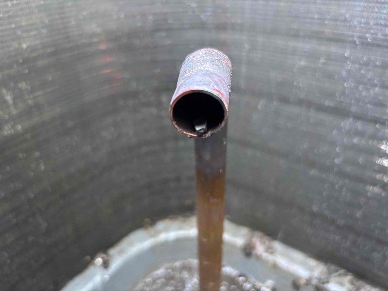# HVAC Noise Diagnosis and Refrigerant Line Repair

Responded to service call for air conditioning unit producing loud unusual noise with diminished cooling capacity. Upon inspection, discovered severely corroded copper refrigerant line with visible oxidation, rust staining, and structural deterioration. The compromised line showed evidence of long-term moisture exposure and mineral deposit buildup, which was causing vibration noise during compressor operation and restricting refrigerant flow.

Removed damaged section of copper refrigerant line and debris from insulation material. The corrosion had progressed to the point where the line integrity was compromised, contributing to both the excessive noise and reduced cooling efficiency. Replaced affected refrigerant line segment with new copper tubing, ensuring proper sizing and secure connections. System tested and confirmed restored cooling performance with elimination of abnormal operating noise.