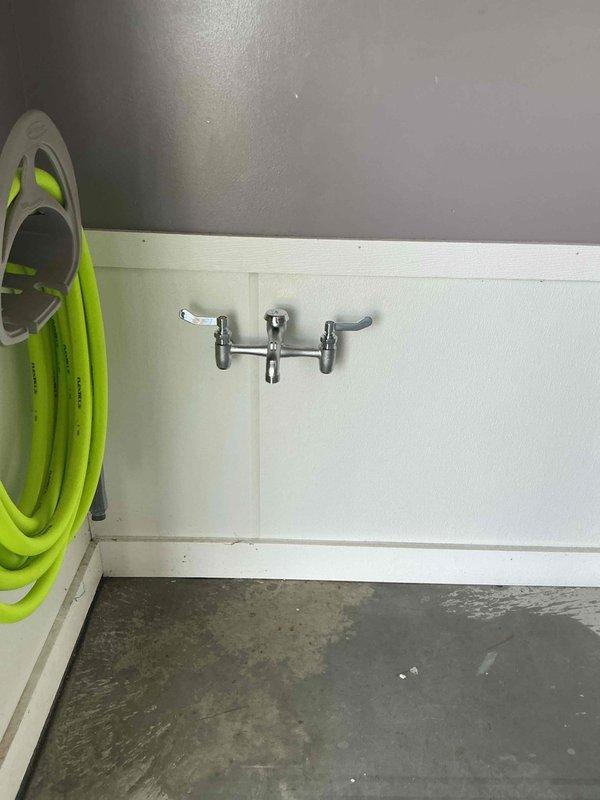 Installed hot and cold frost-proof spigot assembly with dual ball valve shutoffs in interior utility room. Mounted chrome dual-handle wall faucet on lower wall paneling with proper backing and sealed penetrations to prevent water intrusion. Connected supply lines to existing hot and cold water distribution system with individual ball valve isolation for each line to allow independent shutoff capability. Tested both hot and cold water flow, verified frost-proof operation, and confirmed all connections are leak-free.