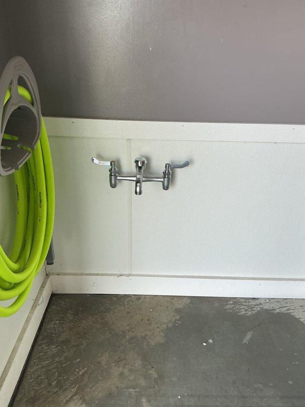Installed hot and cold frost-proof spigot assembly with dual ball valve shutoffs in interior utility room. Mounted chrome dual-handle wall faucet on lower wall paneling with proper backing and sealed penetrations to prevent water intrusion. Connected supply lines to existing hot and cold water distribution system with individual ball valve isolation for each line to allow independent shutoff capability. Tested both hot and cold water flow, verified frost-proof operation, and confirmed all connections are leak-free.