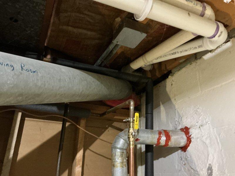 Completed comprehensive rental inspection of 7-year-old Rheem HVAC system and water heating equipment in basement utility area. Documented all mechanical systems including green-painted furnace unit with PVC condensate drainage configuration, gray water heater with proper labeling, copper supply lines, and flexible ductwork routing. Photographed equipment specifications, piping connections with purple primer marks at joints, brass valve assemblies, and PVC pipe distribution system labeled for room identification throughout the property.