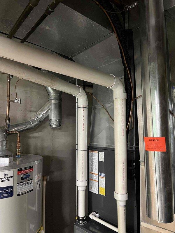 Conducted a no-charge indoor air quality assessment and documentation of existing HVAC system and mechanical equipment. Photographed and evaluated the mechanical room installation, including Bradford White water heater, furnace/air handler unit with intake and exhaust PVC venting, and associated ductwork systems. Inspected vertical drain/vent lines, insulated ductwork, and overall equipment configuration in the basement mechanical space. Provided visual documentation of current system layout and equipment conditions for customer records and future service reference.