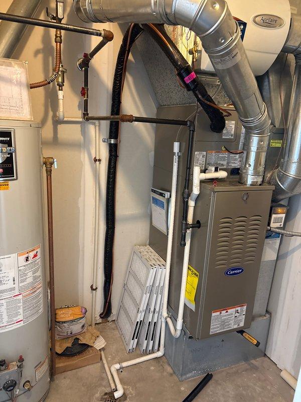 Completed full HVAC system installation including new Carrier furnace and air conditioning unit in residential mechanical room. Installed all necessary ductwork, PVC condensate lines, electrical connections, and integrated AprilAire humidifier system. Verified proper clearances around water heater, tested all safety controls, and confirmed system operation meets manufacturer specifications.