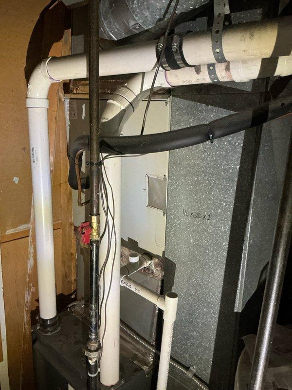 Responded to service call for air conditioning system unable to maintain desired temperature at thermostat setting. Performed diagnostic evaluation of HVAC system including inspection of furnace/air handler unit, ductwork distribution, and attic-mounted components. Documented existing equipment configuration showing gray metal air handler with associated PVC drainage lines, flexible ductwork connections, and metallic supply ducts running through attic space with fiberglass insulation. System is over five years old and currently underperforming on cooling capacity, requiring further assessment to determine whether issue stems from refrigerant levels, airflow restrictions, or equipment degradation.