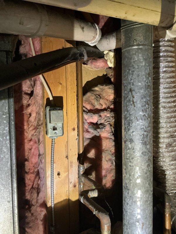 Responded to service call for air conditioning system unable to maintain desired temperature at thermostat setting. Performed diagnostic evaluation of HVAC system including inspection of furnace/air handler unit, ductwork distribution, and attic-mounted components. Documented existing equipment configuration showing gray metal air handler with associated PVC drainage lines, flexible ductwork connections, and metallic supply ducts running through attic space with fiberglass insulation. System is over five years old and currently underperforming on cooling capacity, requiring further assessment to determine whether issue stems from refrigerant levels, airflow restrictions, or equipment degradation.