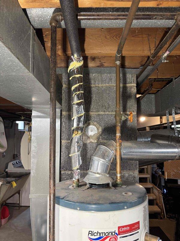 Completed water heater replacement estimate for a 9-year-old unit located in basement utility area. Assessed existing conventional water heater installation, reviewed plumbing connections including copper supply lines and galvanized distribution piping, and evaluated venting configuration with white flue pipe extending through ceiling joists. Discussed heat pump water heater options with customer, comparing energy efficiency ratings, available utility rebates, and operational cost savings versus standard electric or gas units. Reviewed installation requirements including potential electrical upgrades, condensate drainage provisions, and adequate clearance space for heat pump operation in basement environment.