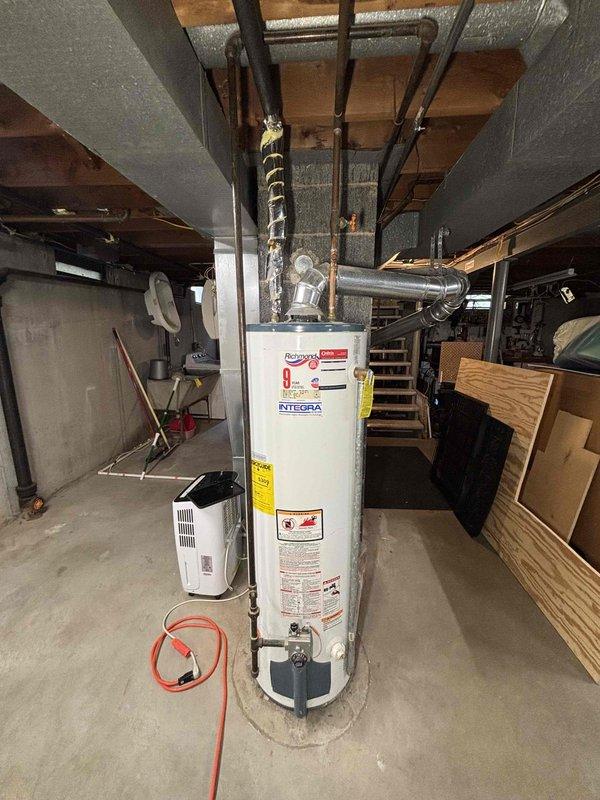 Completed water heater replacement estimate for a 9-year-old unit located in basement utility area. Assessed existing conventional water heater installation, reviewed plumbing connections including copper supply lines and galvanized distribution piping, and evaluated venting configuration with white flue pipe extending through ceiling joists. Discussed heat pump water heater options with customer, comparing energy efficiency ratings, available utility rebates, and operational cost savings versus standard electric or gas units. Reviewed installation requirements including potential electrical upgrades, condensate drainage provisions, and adequate clearance space for heat pump operation in basement environment.
