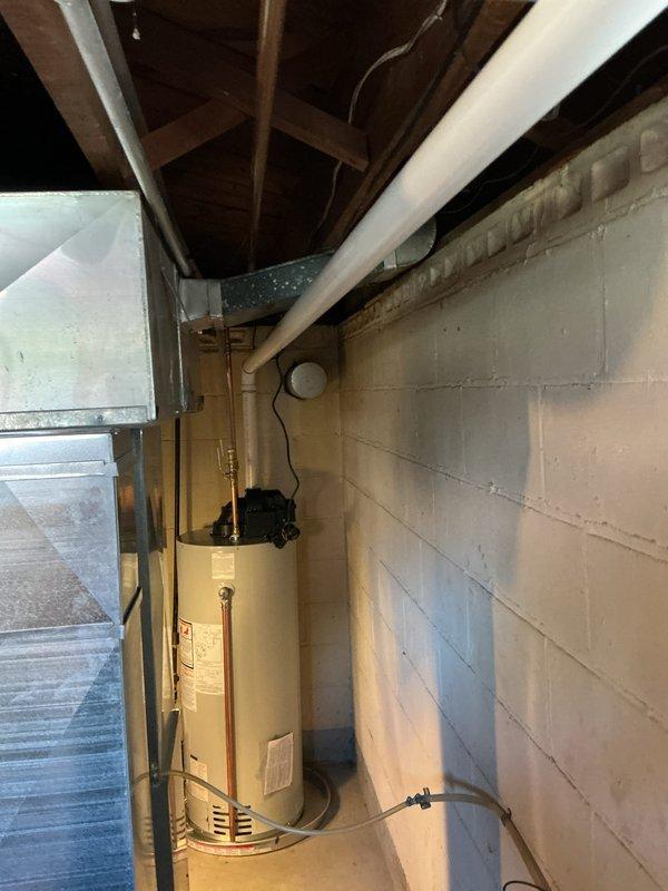 Completed installation of a 40-gallon power vent water heater in residential basement utility area. Unit was properly positioned on concrete floor against cinder block wall, with all copper supply lines, brass shut-off valves, electrical connections, and venting ductwork installed per manufacturer specifications and local code requirements.