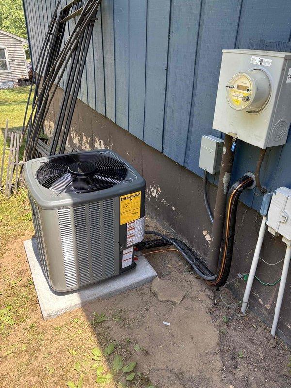 Successfully completed full air conditioning system replacement at residential property with blue vertical siding. Removed existing AC condenser unit and installed new gray condensing unit on existing concrete pad. Connected refrigerant lines with proper black insulation wrapping and secured all copper line sets along exterior wall to indoor air handler. Completed all electrical connections to existing meter base and verified proper voltage supply. Tested system operation including compressor startup, fan motor function, and refrigerant pressures to manufacturer specifications. All components operational and system cooling effectively upon completion.