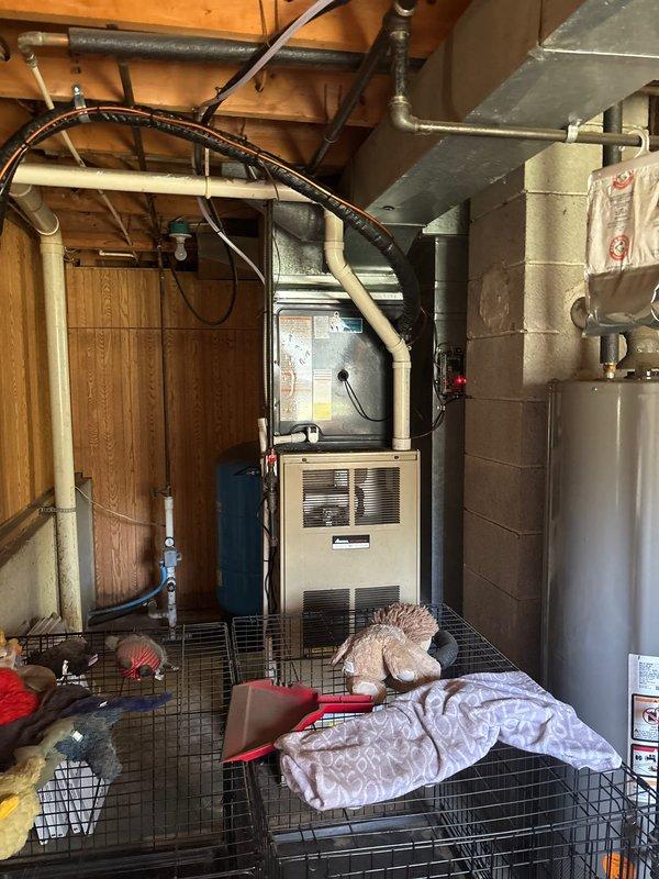 Completed full air conditioning system replacement at residential property. Removed existing outdoor condensing unit and installed new AC condenser on concrete pad against exterior wall with proper refrigerant line connections routed up exterior siding to indoor air handler. Connected system to existing furnace and ductwork in basement utility area, verified proper electrical connections, charged system to manufacturer specifications, and tested all components for proper operation and airflow.