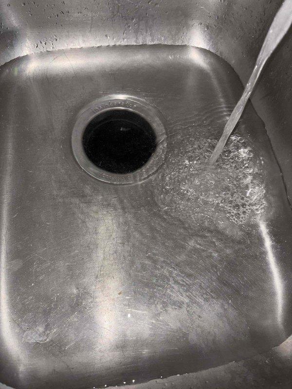 Responded to service call for leaking garbage disposal. Upon arrival, confirmed disposal was leaking when water was run into that side of the sink. Inspected unit and mounting assembly under sink. Documented existing conditions with photos showing disposal installation and sink basin. Completed diagnostic evaluation of disposal unit and plumbing connections to identify source of leak.