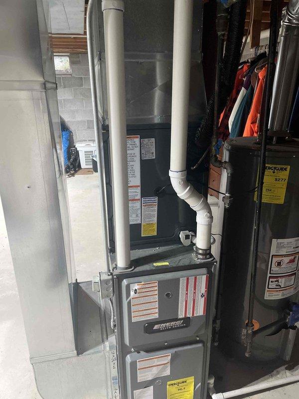 Completed full air conditioning system replacement including outdoor condensing unit and indoor air handler integration with existing furnace system. Installed new outdoor condenser on concrete pad with proper refrigerant line connections, electrical disconnect, and weatherproof penetration through exterior wall. Connected refrigerant lines with black insulation, established proper electrical service, and integrated system with indoor furnace unit. Verified all mechanical connections, tested system operation, and confirmed proper airflow and cooling performance upon startup.