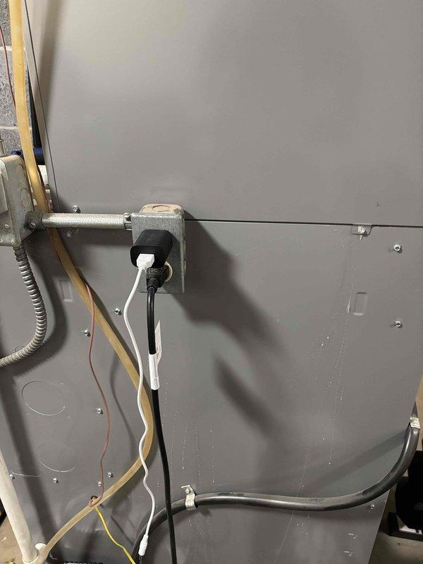 Responded to water leak complaint around furnace area, potentially originating from humidifier clear tube assembly. Inspected 15-year-old comfort system and located furnace unit with humidifier installation. Examined electrical connections, junction box, and wiring routing on equipment panel. Documented equipment condition and potential leak source areas with photographs for service records.