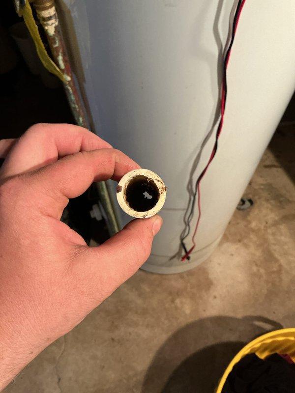 Responded to service call for 12-year-old air conditioning unit with non-operational fan affecting entire system. Upon inspection, discovered severely corroded and mineral-clogged copper piping with significant internal buildup restricting flow. Documented existing wiring configuration and outdoor unit installation showing disorganized electrical connections and weathered components requiring attention. Photographed deteriorated pipe section displaying heavy scale deposits and reduced internal diameter due to hard water conditions and age-related corrosion.