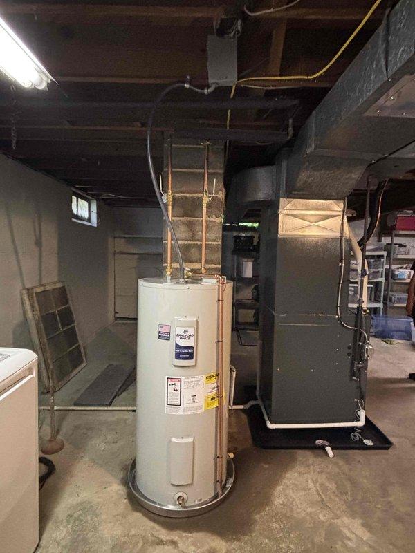 Completed full HVAC system installation including new furnace, air conditioning unit, and water heater. Installed outdoor AC condenser unit on concrete pad with proper refrigerant line connections and performed system charging and pressure testing using manifold gauges to verify proper operation. In basement mechanical room, installed new gas furnace with ductwork connections and white cylindrical water heater with copper supply piping, ensuring all units were properly positioned, vented, and connected to existing utility infrastructure per manufacturer specifications and local code requirements.