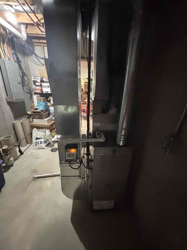 Completed full HVAC system installation in residential basement utility area. Installed new furnace unit with integrated control panel and digital display, connected to white-painted supply ductwork extending vertically and horizontally throughout the space. Configured all ductwork connections including rectangular trunk line and cylindrical branch ducts to ensure proper airflow distribution. Positioned equipment on concrete pad in mechanical room, verified all electrical connections to panel, and confirmed proper venting. System tested and operational upon completion with all manufacturer specifications met.