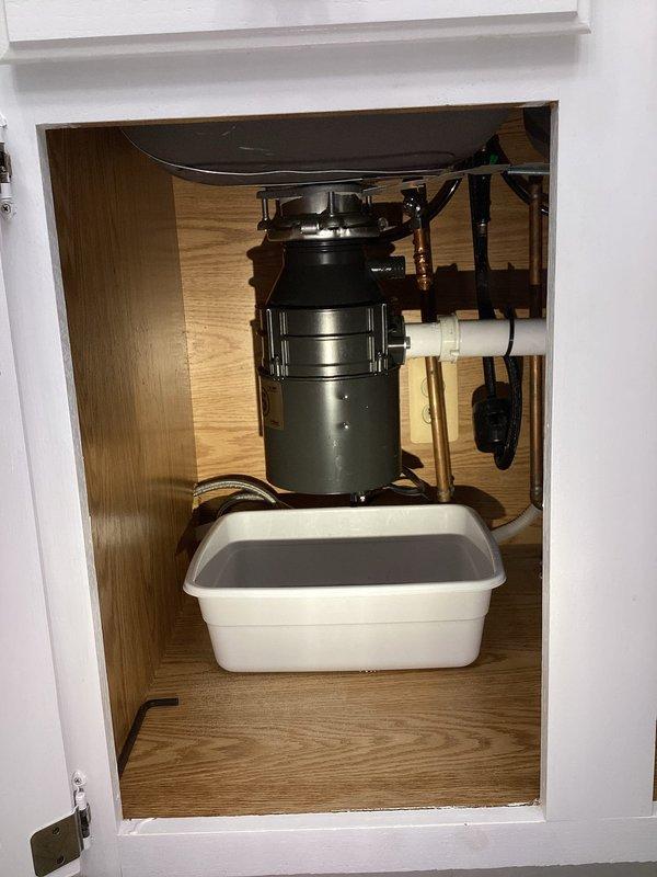 # Garbage Disposal Installation

Completed installation of new garbage disposal unit under kitchen sink. Removed existing disposal and connected replacement unit to sink drain with proper mounting flange assembly. Established electrical connection to dedicated outlet within cabinet. Connected white PVC discharge piping from disposal to existing drain line and secured dishwasher drain connection to disposal inlet. Verified all plumbing connections for proper seal and tested disposal operation under running water to confirm proper function and drainage. Placed leak detection tray beneath disposal unit as precautionary measure. System operating properly with no leaks detected.