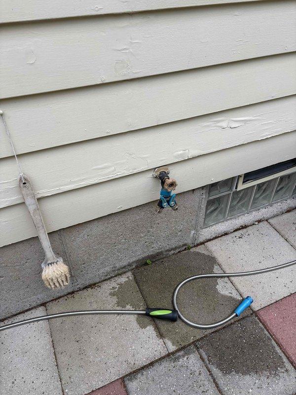 Completed replacement of exterior hose bib on building with horizontal siding. Removed aged copper-colored fixture showing oxidation and installed new hose bib, restoring proper function to outdoor water supply connection.