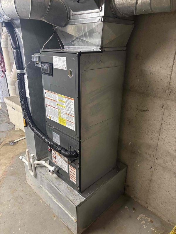 Completed full installation of residential HVAC system including air handler and condensing unit in basement utility space. Installed new furnace cabinet with proper clearance on concrete platform, connected metallic supply ductwork and black flexible return ducting, and established PVC condensate drainage piping. System was properly mounted, all ductwork connections secured, electrical and refrigerant lines run between indoor and outdoor units, and equipment tested for proper operation upon startup.