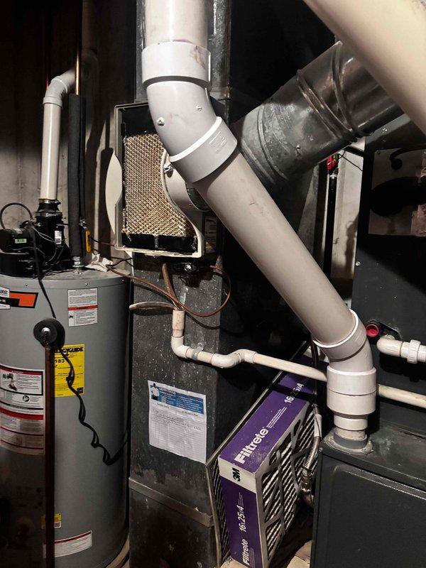Responded to service call for 6-year-old Bryant air conditioning system not adequately cooling residence. Upon arrival, performed comprehensive system inspection including evaporator coil, condensate drainage, and airflow components. Inspected evaporative cooling media and verified proper installation of PVC ventilation piping and mounting hardware. Evaluated control unit functionality and system operation parameters. Documented equipment condition through photographic records showing mechanical room configuration, water heater proximity, and HVAC component arrangement. System assessed for cooling capacity and operational efficiency to determine cause of inadequate temperature control.