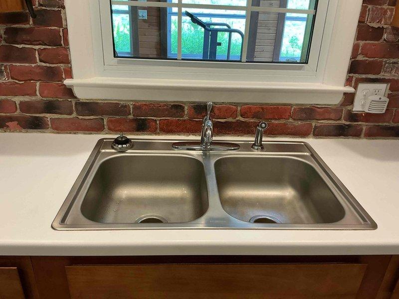 Completed comprehensive plumbing repairs addressing multiple fixture issues throughout the property. Repaired leaking kitchen sink faucet and dripping sprayer attachment, performed thorough cleaning and maintenance of shower head and handle assembly to restore proper water flow, and installed outdoor faucet extension for improved accessibility. Additionally, diagnosed and repaired washing machine water supply leak, which included addressing severely frosted refrigerant lines and pipe connections that had accumulated excessive ice buildup in the crawl space area, indicating a significant temperature differential issue that was resolved during the service call.