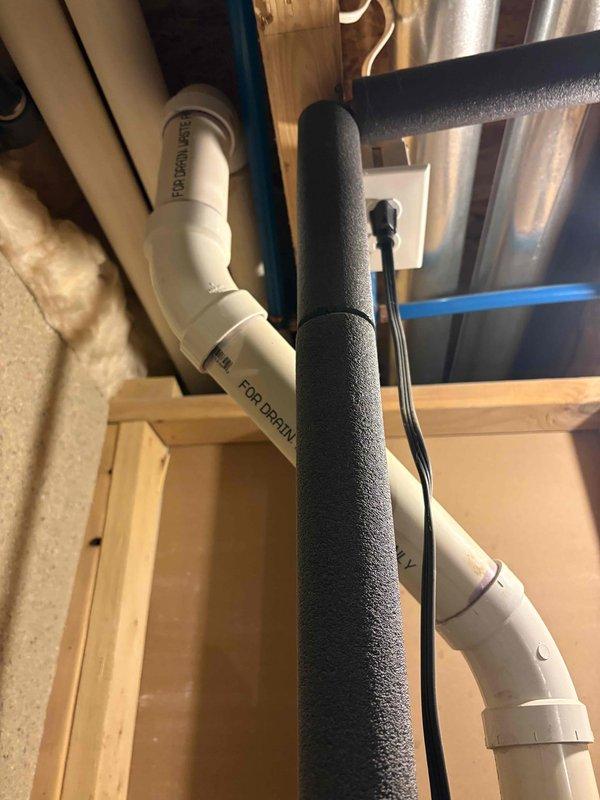 Responded to water heater leak at sweat joint on 11-year-old unit in owner-occupied residence. Upon arrival, customer had already shut off water supply due to active leak. Inspected copper piping connections and identified failed sweat joint as source of leak. Unit was producing hot water prior to shutdown but required immediate attention to prevent water damage. Documented plumbing configuration including PVC drain lines, copper supply lines with shutoff valve, and insulated piping within wooden frame structure. Photographed leak location and surrounding plumbing infrastructure for service records.
