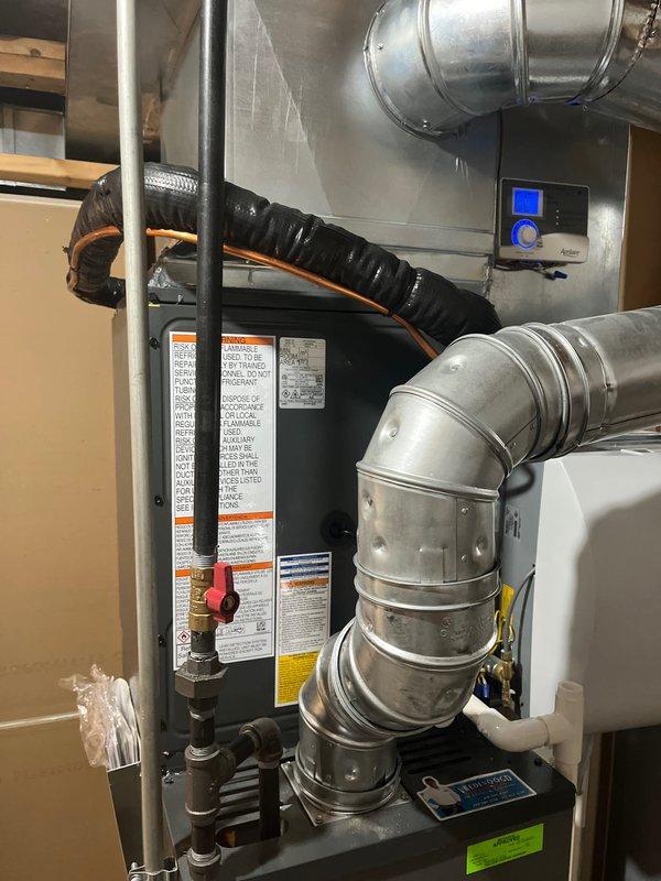 Completed full HVAC system replacement including outdoor condensing unit and indoor air handler. Installed new gray condensing unit on existing concrete pad with proper clearances from foundation and landscaping. Connected refrigerant lines, electrical service, and condensate drainage per manufacturer specifications. Mounted new air handler in basement utility area with integration to existing ductwork system, including galvanized supply and return plenums. Installed new digital thermostat control for system operation. Verified proper airflow, refrigerant charge, and electrical connections. System tested and operational upon completion.