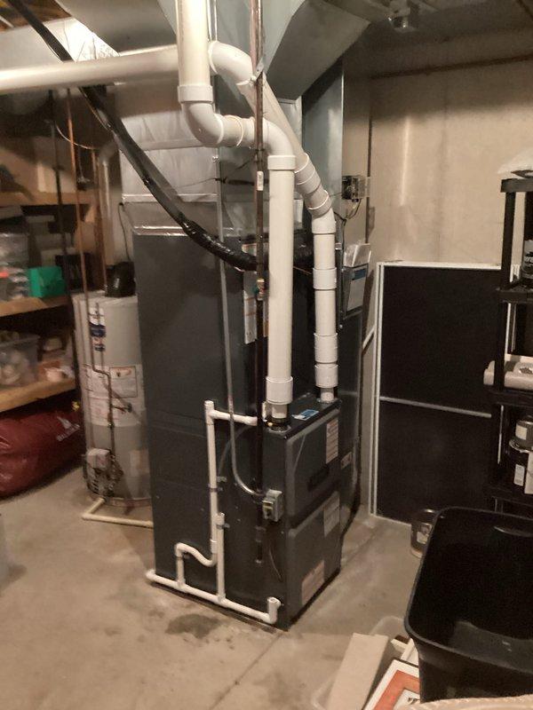 Successfully completed full HVAC system replacement including outdoor condenser unit and indoor furnace. Removed existing equipment and installed new gray condenser unit on exterior with proper refrigerant line connections, copper piping, and black insulation. Configured all plumbing connections and secured unit against exterior wall with appropriate clearances. Indoor installation included new furnace unit in basement utility area with associated PVC venting system routed vertically for proper exhaust. Connected all electrical components, refrigerant lines, and ductwork to complete system integration. Verified all connections, tested system operation, and confirmed proper airflow throughout. Work area cleaned and all debris removed upon completion.