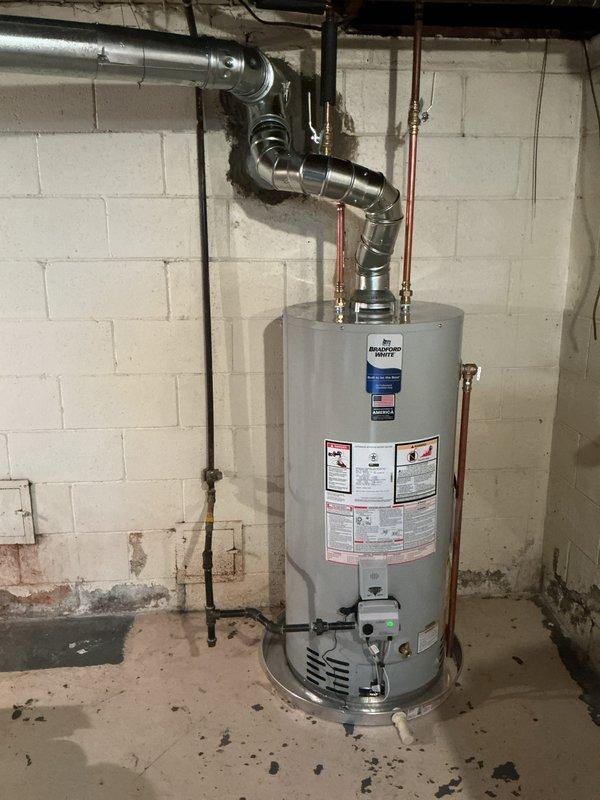 Completed installation of a 40-gallon Bradford White natural gas water heater in basement utility room. Unit was properly vented with metallic vent pipe, connected to existing copper supply lines with brass fittings, and installed according to manufacturer specifications and local code requirements.