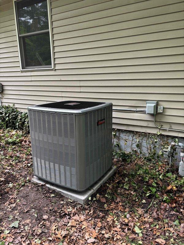 Successfully completed add-on air conditioning system installation at residential property. Installed new outdoor condensing unit with gray metal casing on concrete pad against exterior wall with beige vinyl siding. Mounted electrical disconnect box to building exterior per code requirements. Ran refrigerant line set consisting of insulated copper suction line and liquid line from condensing unit to building penetration, properly secured to siding with appropriate brackets and fasteners. Installed black flexible conduit for electrical connections. All refrigerant lines properly insulated and secured. System positioned for optimal airflow and serviceability. Installation completed per manufacturer specifications and local building codes. Unit operational and ready for service.