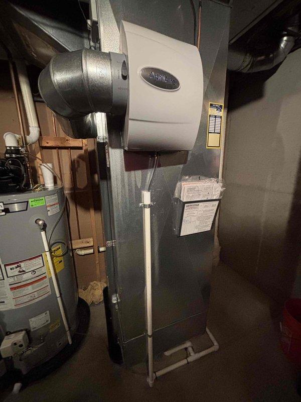 Completed full HVAC system installation including new Amana air conditioning unit and furnace with Aprilaire humidifier integration. The outdoor AC condenser was positioned on a concrete pad with proper gravel base and electrical conduit run, while the indoor furnace was installed in the basement mechanical room with all necessary ductwork connections and humidification system properly integrated into the supply plenum.