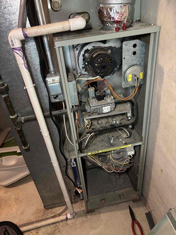 Responded to no-cooling complaint on residential air conditioning system. Upon arrival, confirmed air handler blower motor was inoperative while heating function remained intact. Performed diagnostic inspection of furnace and air handler assembly, removing access panels to assess internal components including blower assembly, control board, and electrical connections. Documented existing equipment condition with photographs showing internal components, wiring configuration, and overall system age. System exhibits signs of advanced wear consistent with aging HVAC equipment. Customer advised of findings and provided recommendations for repair or replacement options given the age and condition of the unit.