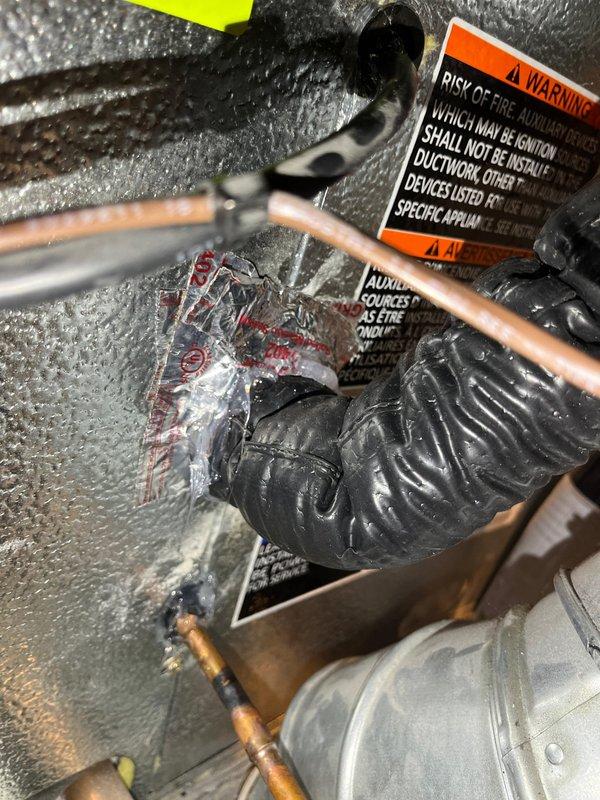 Completed CORR inspection corrections by installing proper insulation at the evaporator coil and installing line set grommets where refrigerant lines penetrate through surfaces. Documented corrected installation with photos showing properly insulated copper refrigerant lines and grommets in place per inspector requirements.