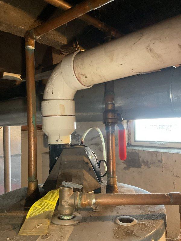 Provided estimate for replacement of existing Richmond 6-year warranty water heater located in basement utility area. Unit is secured with blue metal straps and features standard copper supply piping with brass shut-off valve and white PVC venting system. Documented current installation configuration including piping layout, venting arrangement, and equipment accessibility for replacement proposal.
