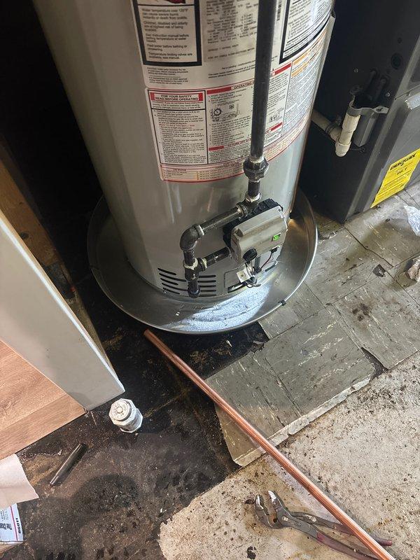 Completed installation of a 40-gallon natural draft natural gas water heater (tall tank, 56 5/8") with recirculation pump system in utility area. Installation included proper gas control valve assembly, copper supply and discharge piping with brass fittings, and integration of existing recirculation system with pump mounted atop the unit. All connections were secured, system was tested for proper operation, and installation was completed with 6-year parts and 1-year labor warranty coverage.