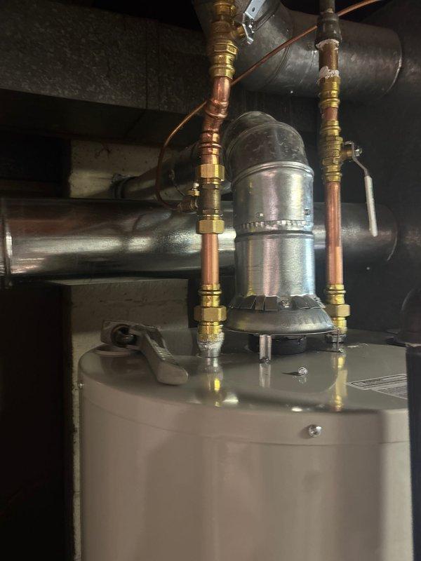 Completed installation of a 40-gallon natural draft natural gas water heater (tall tank, 56 5/8") with recirculation pump system in utility area. Installation included proper gas control valve assembly, copper supply and discharge piping with brass fittings, and integration of existing recirculation system with pump mounted atop the unit. All connections were secured, system was tested for proper operation, and installation was completed with 6-year parts and 1-year labor warranty coverage.