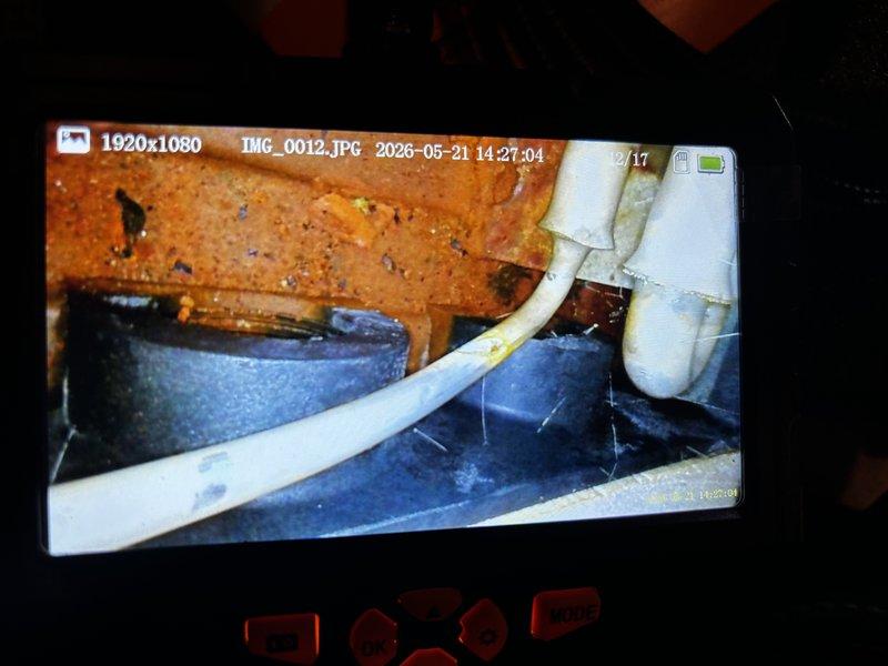 Responded to no-cool condition on 6-year-old unit following previous service visit where UV dye was added to refrigeration system for leak detection. Performed UV light inspection of refrigerant lines and system components, identifying leak location at line set connections. Unit found inoperative due to low refrigerant charge from active leak. Documented findings with UV photography showing fluorescent dye evidence at piping penetrations through base platform.