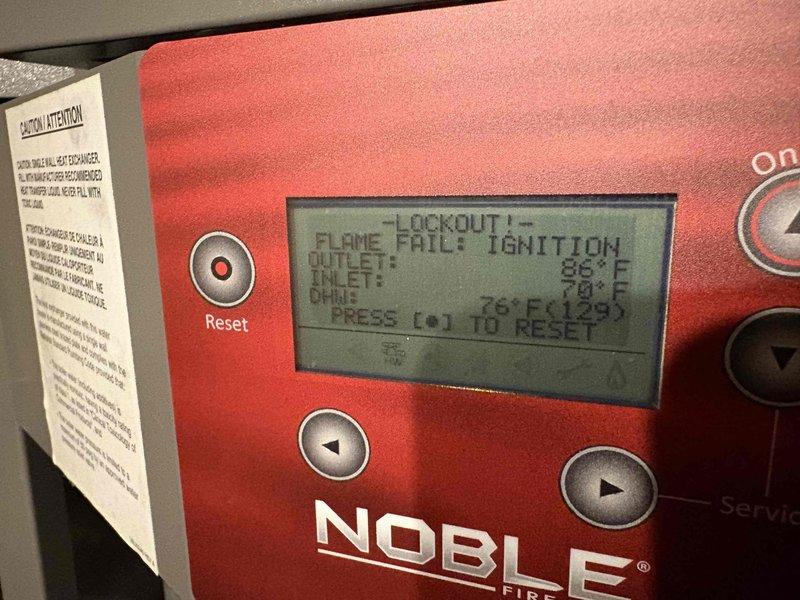 Responded to no hot water complaint on 7-year-old Lochinvar WT 12-2028 boiler system. Upon arrival, found unit in lockout status with flame failure at ignition displayed on control panel. Performed diagnostic assessment and reset procedures per manufacturer specifications. Documented system conditions with photographs showing control panel error codes and related plumbing configuration for service records.