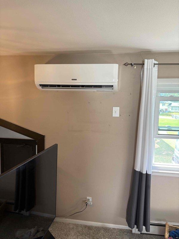 Successfully completed installation of ductless mini-split air conditioning system in residential living space. Mounted indoor evaporator unit on interior wall at optimal height for efficient air distribution, ensuring proper clearance from ceiling and adjacent doorways. Installed unit between window and entertainment area with professional wire management and secure wall mounting. System tested and verified operational, providing climate control capability to the living space.