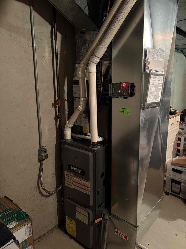 Completed full air conditioning system replacement at residential property. Removed existing AC unit and installed new Trane air conditioning system on exterior concrete pad with proper positioning adjacent to electrical meter and service panel. Installed new air handler unit in basement utility area alongside existing furnace, ensuring proper clearances and access for future maintenance. Ran white PVC condensate drainage piping from air handler with appropriate pitch and routing through basement ceiling joists. Connected electrical service via conduit to exterior disconnect and verified proper voltage and amperage at unit. Tested system operation including compressor startup, refrigerant pressures, airflow, and thermostat communication. Confirmed all connections are secure, system is cooling effectively, and installation meets manufacturer specifications and local code requirements.