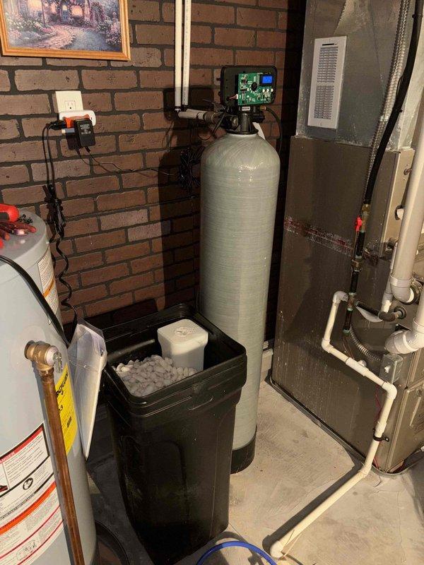 Responded to service call for non-operational water softener system approximately 4 years old. Upon arrival, performed diagnostic assessment of water softening equipment located in basement utility area. Inspected digital control head, brine tank with salt levels, resin tank, and associated plumbing connections including bypass valve and distribution lines. Verified adequate salt pellet supply in brine tank and examined control panel display for error codes or operational indicators. Checked system programming, regeneration cycle settings, and water flow through inlet and outlet connections. Documented existing equipment configuration with water heater and HVAC systems in mechanical room for service records.