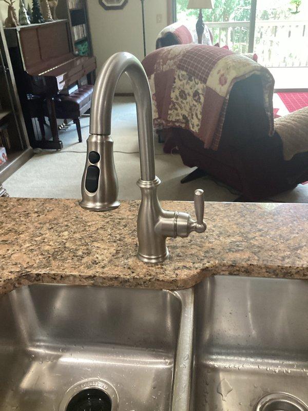 Completed kitchen faucet replacement with customer-supplied fixture on granite countertop with stainless steel double-basin sink. Removed existing faucet assembly, installed new brushed nickel single-handle faucet with pull-down spray head, tested for proper operation and verified no leaks.