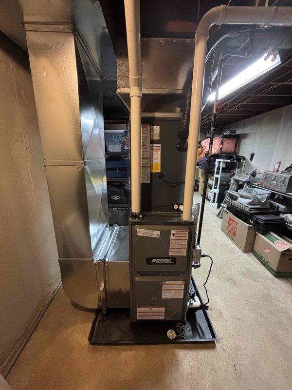 Completed full HVAC system installation including new furnace and air conditioning unit. Installed gray furnace unit in basement on black drip pan with proper PVC venting and ductwork connections to existing system. Mounted outdoor condensing unit on concrete pad with appropriate refrigerant lines, electrical connections, and condensate drainage. Verified all connections, tested system operation, and confirmed proper airflow throughout the residence.