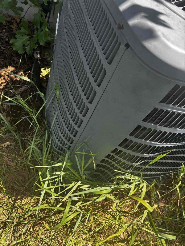 Responded to no heat call for HVAC system not turning on. Upon arrival, located outdoor condensing unit with significant vegetation growth around base and sides, potentially restricting airflow to coil. Unit showed signs of weathering and debris accumulation on exterior surfaces. Performed system diagnostic to determine cause of no operation. Customer reported filters changed regularly. Documented equipment condition with photos showing grass and weeds in close proximity to condenser requiring clearance maintenance. Unit accessibility partially compromised by overgrown landscaping. Assessed electrical components, thermostat communication, and safety controls to identify failure point preventing system startup.