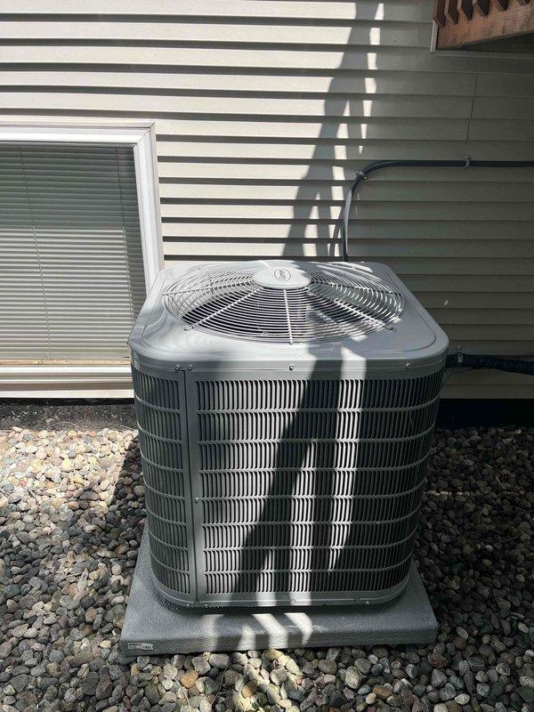 Completed full HVAC system installation including new Carrier furnace and outdoor AC condenser unit. Furnace installed in basement utility room on protective drain pan with humidifier integration, PVC venting, and proper gas line and electrical connections. Exterior condenser unit positioned on concrete pad with refrigerant lines and electrical conduit properly secured to building exterior, complete with all necessary ductwork modifications and system startup.