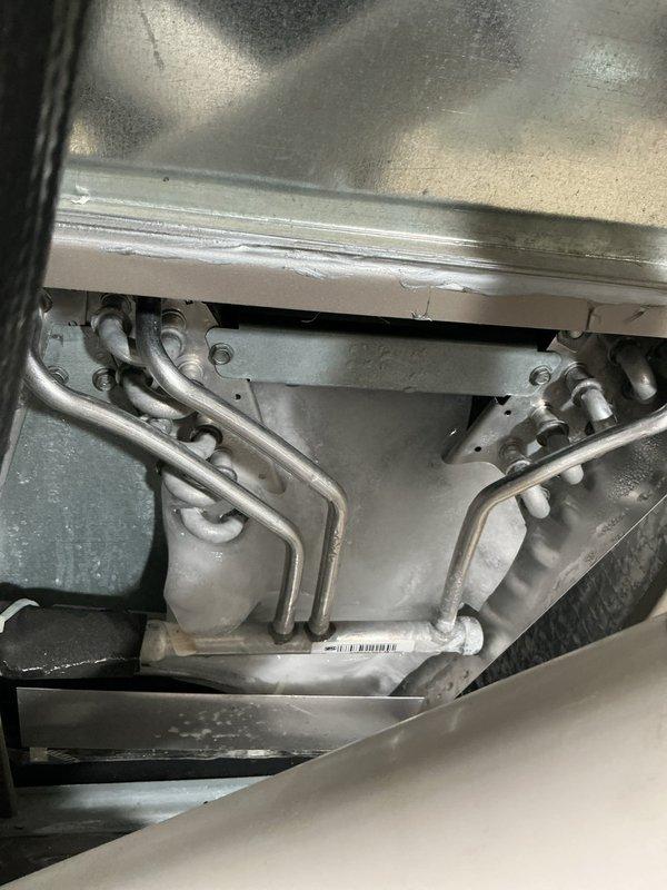 Responded to call for water leakage and reduced cooling performance on a 4-year-old system. Upon inspection, found water discharge from the unit and compromised cooling efficiency. Accessed interior components and examined evaporator coil assembly, refrigerant lines, and condensate drainage system. Inspected heat exchanger coils, mounting brackets, and drain pan for blockages or damage. Documented equipment condition with photos showing coil configuration, refrigerant distribution lines, and condensate collection system. All mechanical components, tubing connections, and mounting hardware were assessed for proper operation and potential sources of water intrusion affecting system performance.