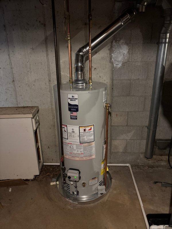 Completed full HVAC system installation including furnace, air conditioning unit, and water heater at residential property. Outdoor AC unit installed on concrete pad adjacent to building exterior with proper clearances and drainage considerations. Bradford White water heater installed in basement utility area with copper supply piping, brass shut-off valves, metallic exhaust venting, and electronic monitoring controls properly configured. All equipment positioned per manufacturer specifications, utility connections established, and systems tested for proper operation upon completion.