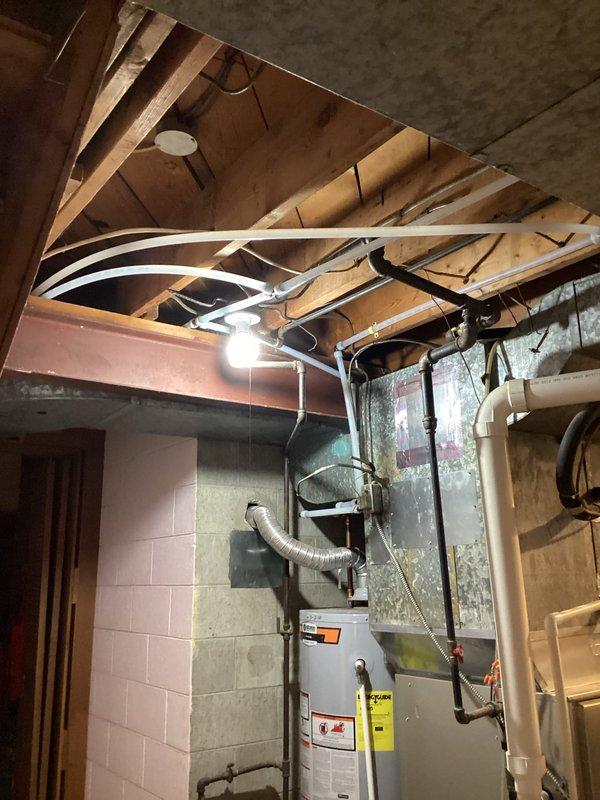 Completed whole house water supply repipe over two-day period with customer occupying residence during work. Installed new copper supply lines throughout home, running vertically through interior wall cavities from basement mechanical room to upper floors. Created access openings in drywall along stairway to route piping through wall framing, with lines properly secured and supported per code requirements. In basement utility area, connected new supply system to water heater and established main distribution manifold among exposed ceiling joists. All piping secured with appropriate hangers and straps to structural members, maintaining proper spacing and slope. System pressure tested and verified operational upon completion.